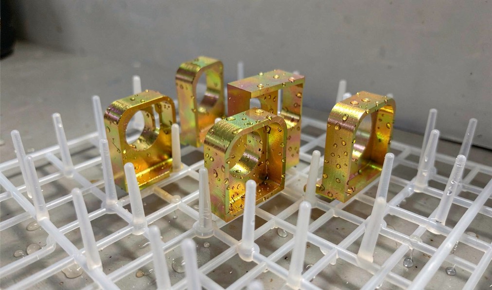 Aluminium brackets with an iridescent golden conversion coating in a drying rack